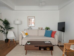 A living room with a sofa, coffee table, lamp, television, and a potted plant. - Renovated apartment in historic center - 5 guests (Sevilla)