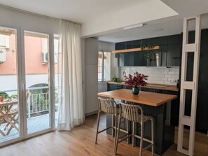 A modern kitchen with a wooden island, two bar stools, and a potted plant. - Renovated apartment in historic center - 5 guests (Sevilla)