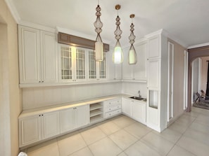 Una cocina con armarios blancos, un banco empotrado e iluminación colgante.