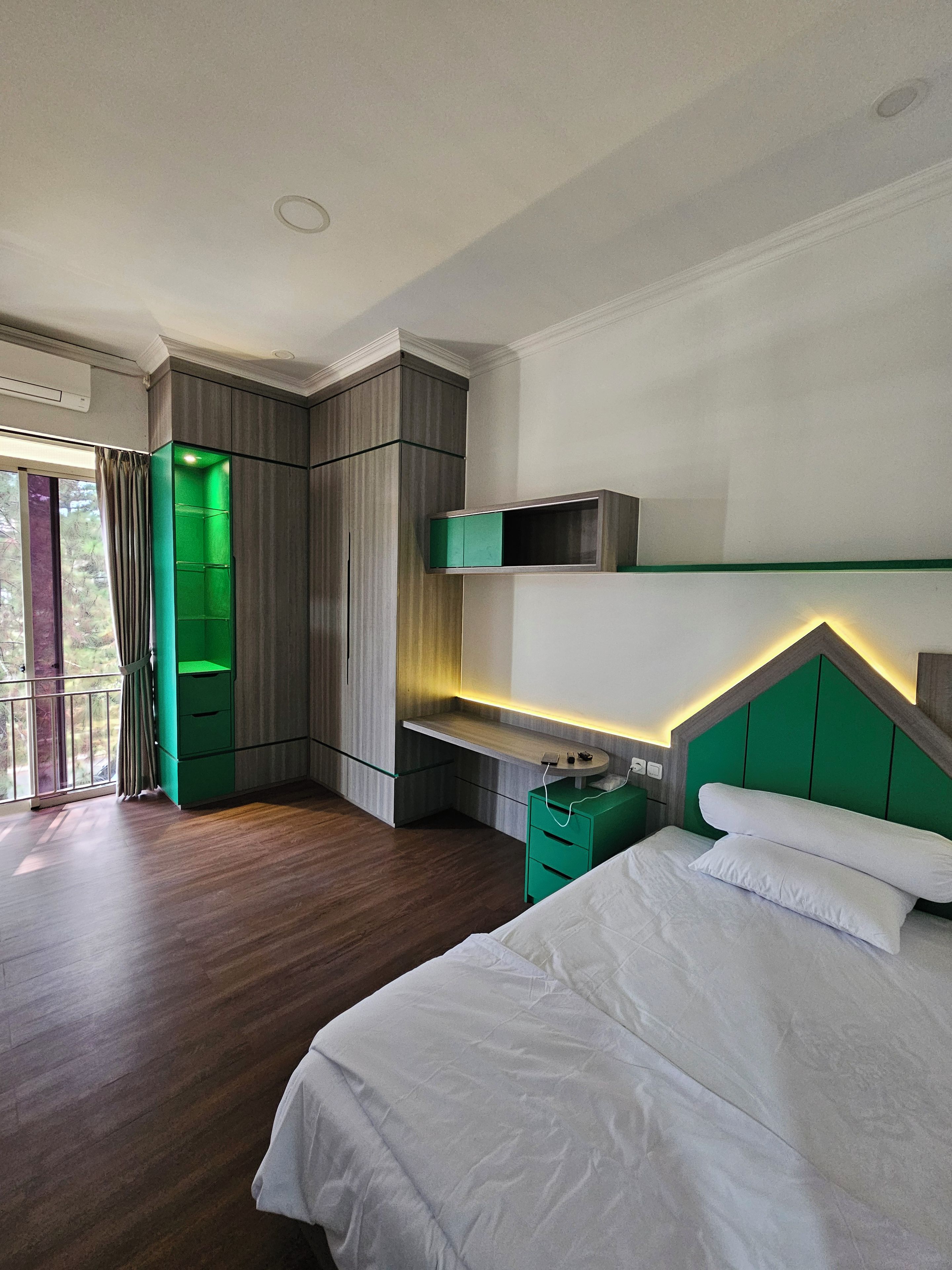 Ein modernes Schlafzimmer mit Bett, Einbauschrank und Balkon.