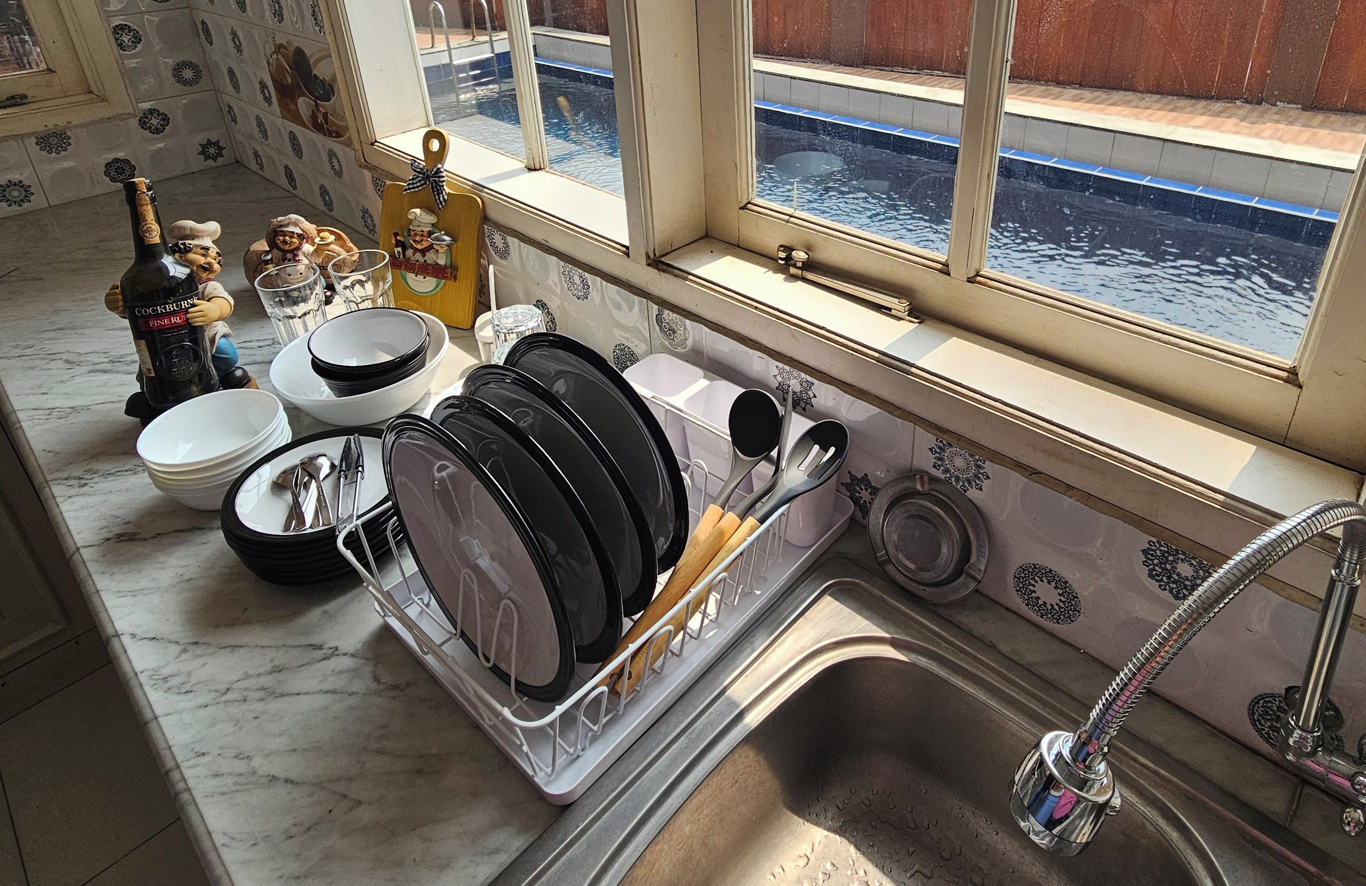 A kitchen with a dish rack, a sink, and a window overlooking a water body.