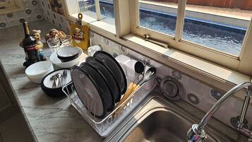 A kitchen with a dish rack, a sink, and a window overlooking a water body.