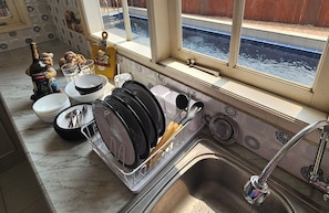 A kitchen with a dish rack, a sink, and a window overlooking a water body.