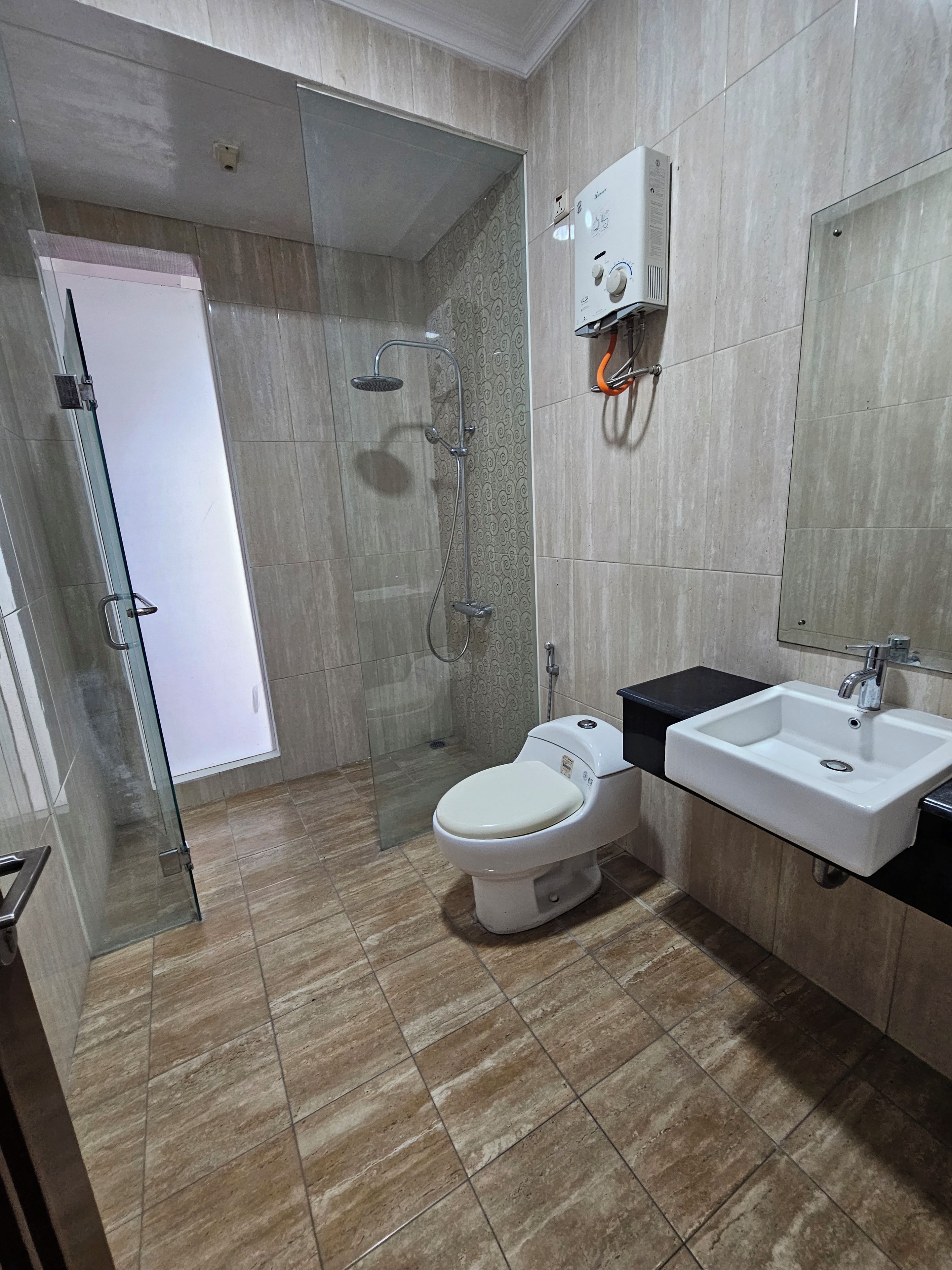 A modern bathroom with a glass shower enclosure, a white toilet, and a sink with a black countertop.