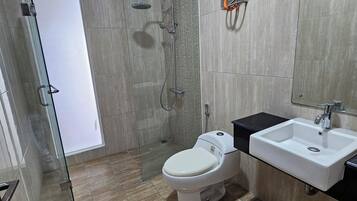 A modern bathroom with a glass shower enclosure, a white toilet, and a sink with a black countertop.