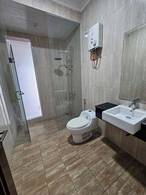 A modern bathroom with a glass shower enclosure, a white toilet, and a sink with a black countertop. - Spacious 6-bedroom townhome in amazing Bandung with AC,swimming pool, BBq etc (Bandung)