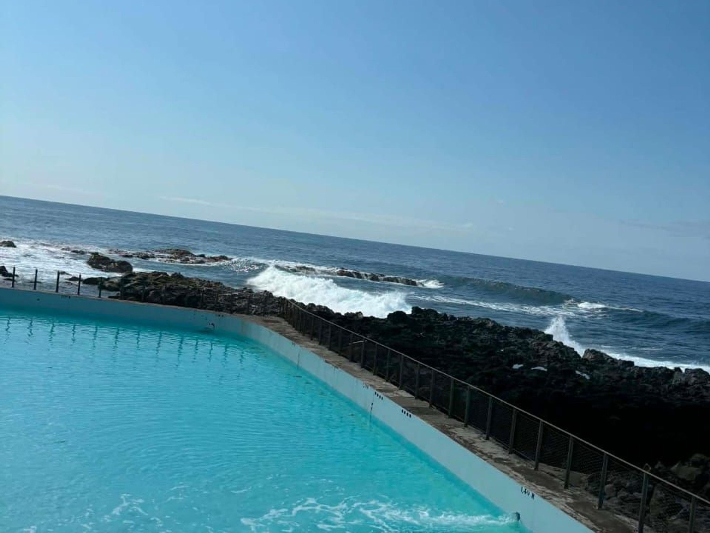 A pool with a view of the ocean and rocky coastline.