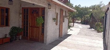 Un edificio con puerta de madera, ventanas y planta colgante.