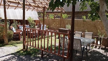 Un espacio de esparcimiento al aire libre con mobiliario de madera y una valla de metal.