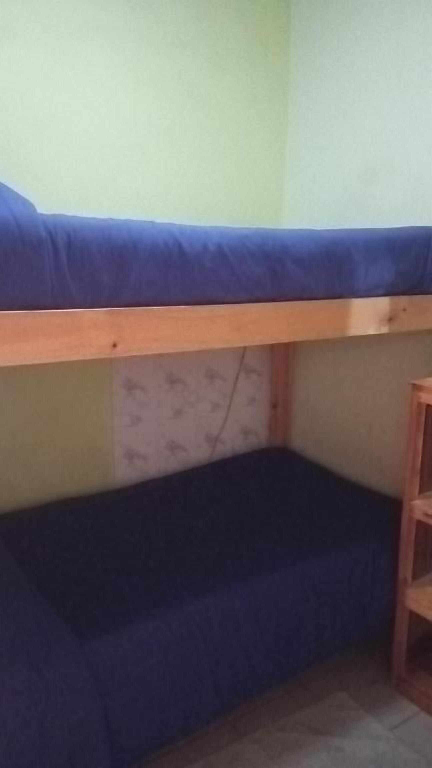 Un lit superposé avec un matelas bleu et une structure en bois.