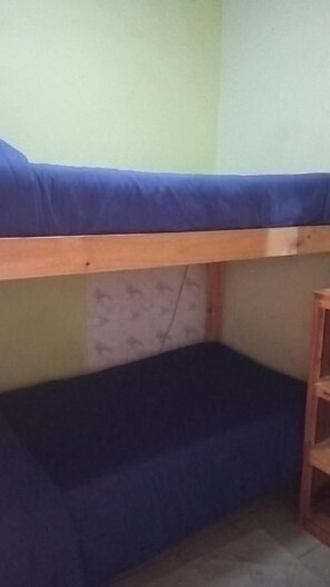 A bunk bed with a blue mattress and a wooden frame.