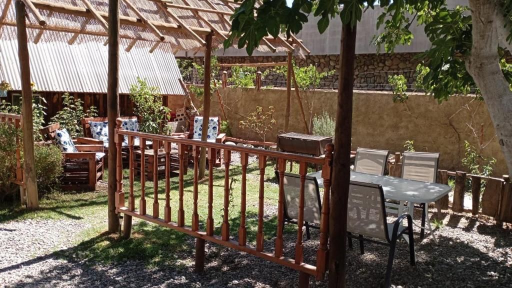 An outdoor seating area with wooden furniture and a metal fence.