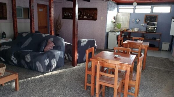A cozy living area with a sofa, wooden dining table, and chairs.