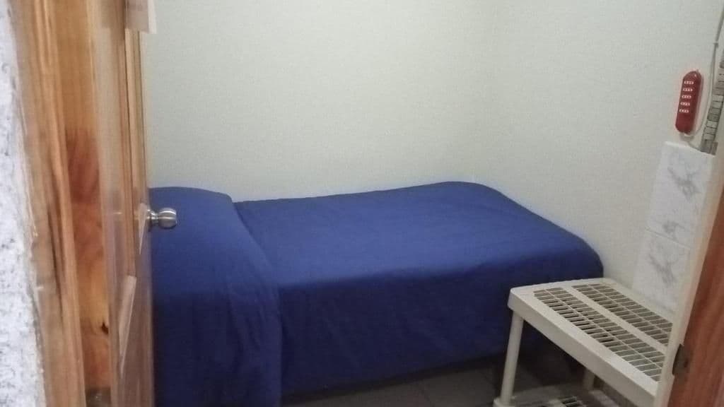 A small room with a single bed, a white radiator, and a door.
