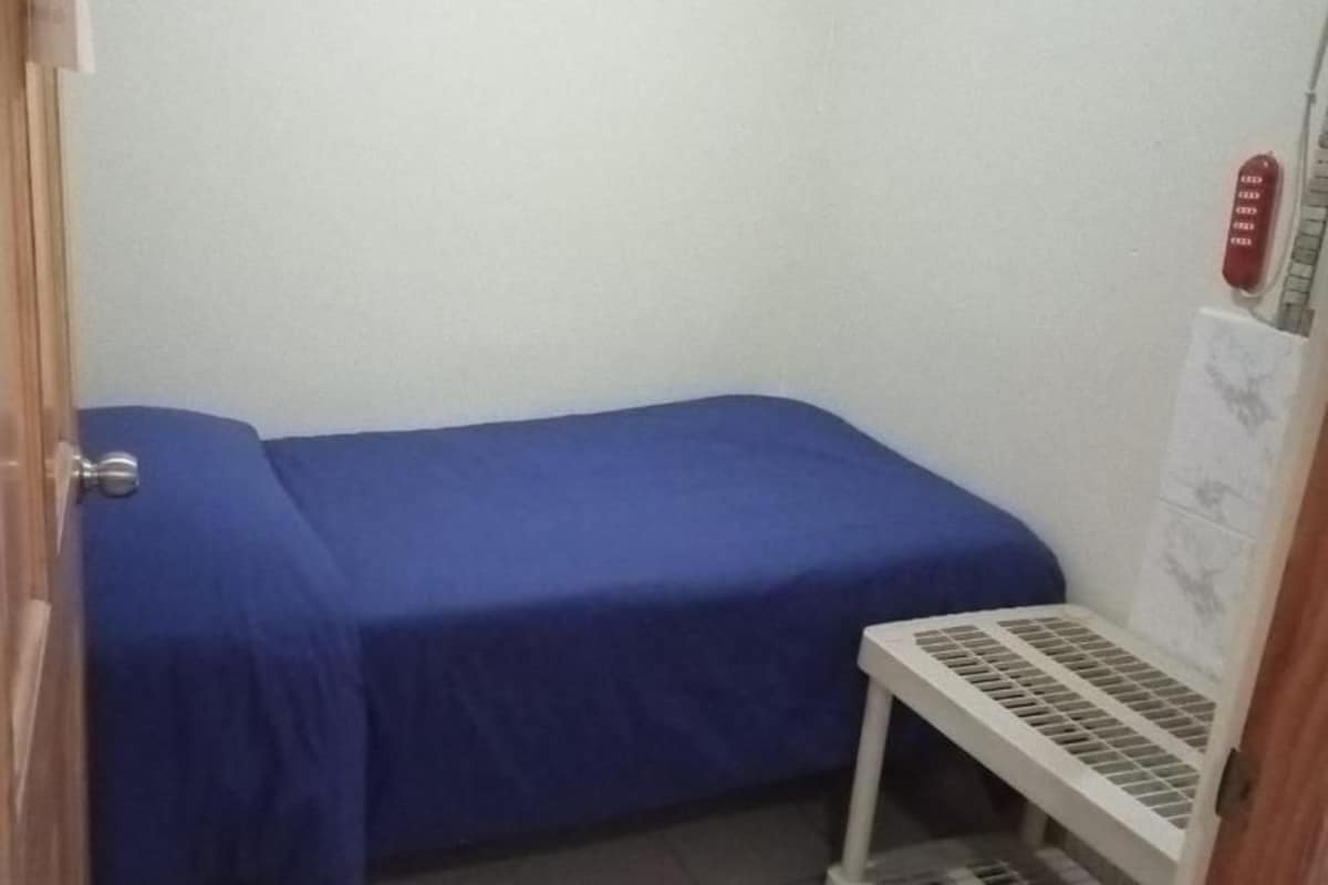 A small room with a single bed, a white radiator, and a door.