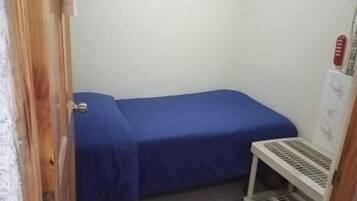 A small room with a single bed, a white radiator, and a door.