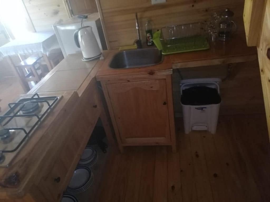 Eine kleine Küche mit Gaskochfeld, Spüle und Mülleimer.