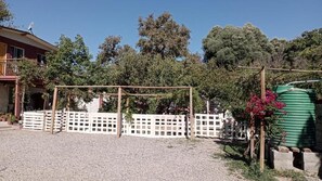 A residential property with a fenced yard, a green water tank, and a house with a satellite dish.