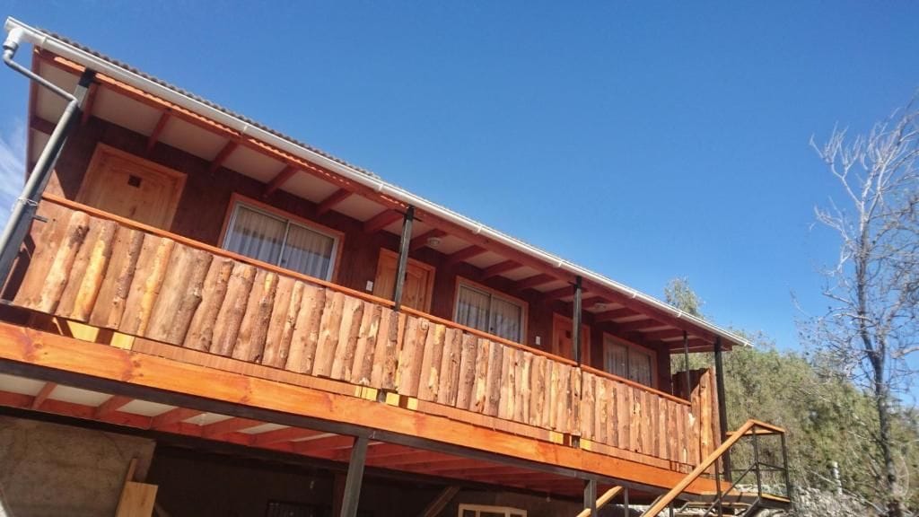 Una cabaña de madera con balcón, ventana y puerta.