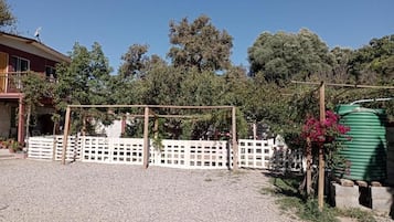 A residential property with a fenced yard, a green water tank, and a house with a satellite dish.