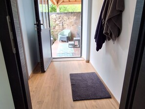 A hallway leading to a patio with a stone wall, a small table, and a chair. - Charming house between Epinal and Vittel - 4 guests (Ville-sur-Illon)
