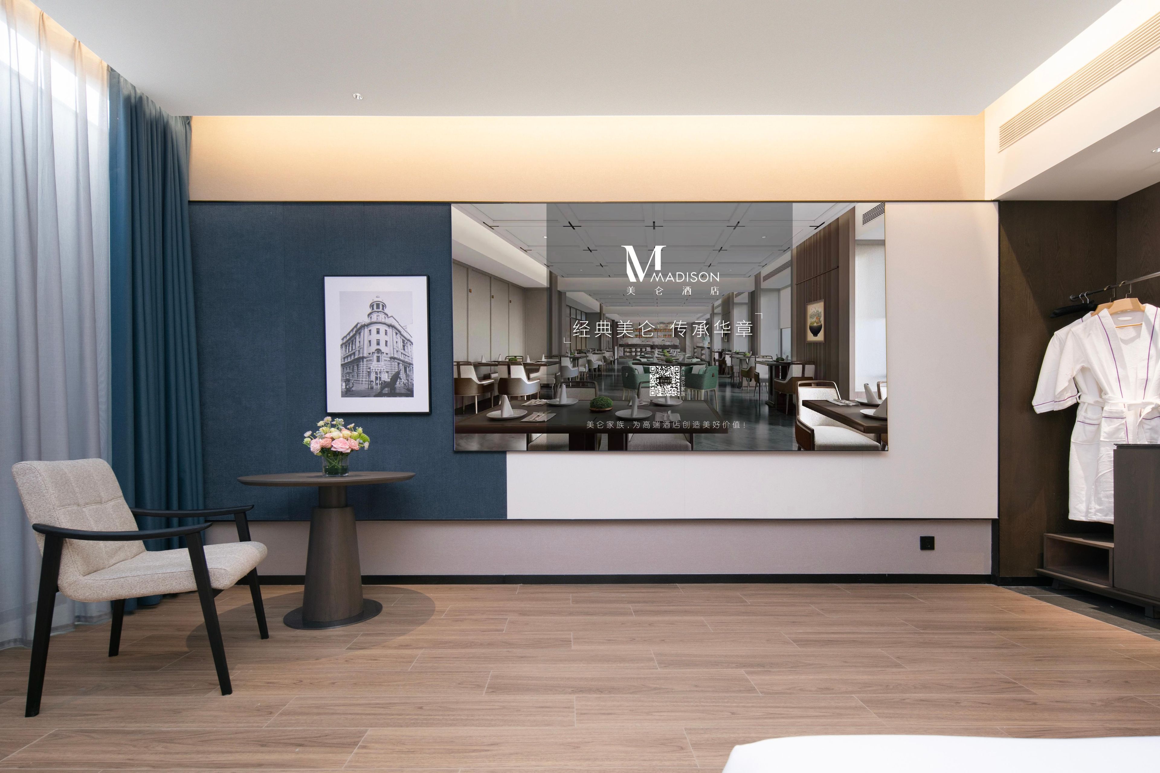 A modern hotel lobby with a seating area, a mirror reflecting the interior, and a QR code for information.