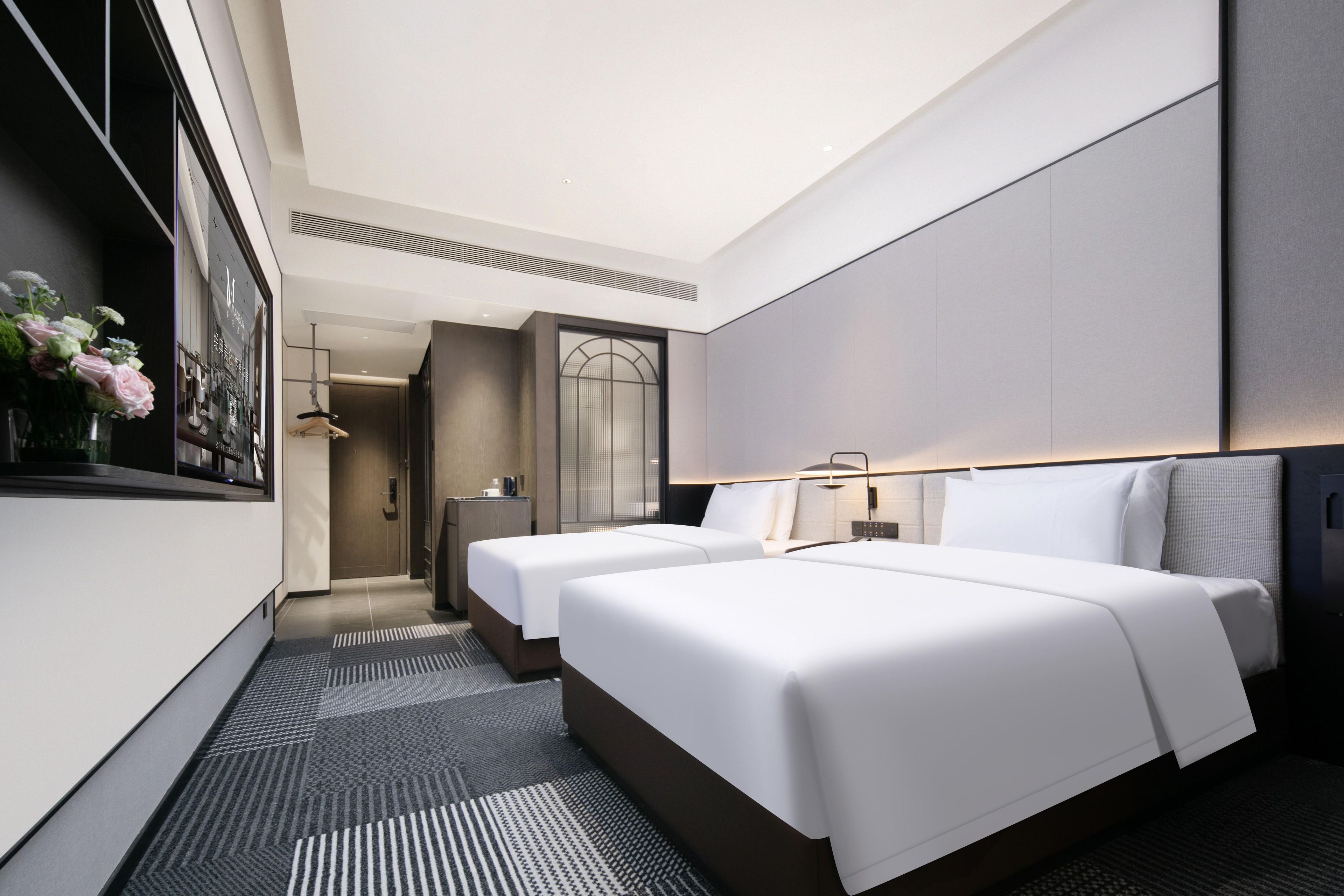 Een hotelkamer met twee bedden, een grote spiegel, een klein bureau en uitzicht op de stad.