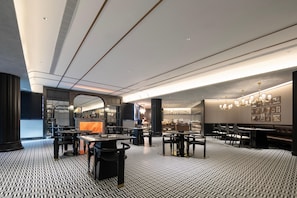 A modern restaurant interior with a patterned floor, black and white furnishings, and a bar area.