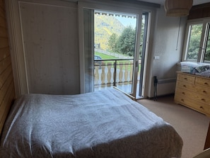 Ein Schlafzimmer mit Bett, Schminktisch und Blick auf einen Balkon mit Holzgeländer.