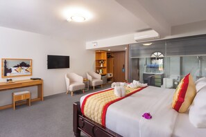 Ein Hotelzimmer mit einem großen Bett, einem Schreibtisch, einem Stuhl, einem Fernseher und einem Kleiderschrank.