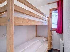 Ein Etagenbett mit Holzrahmen und weißer Bettwäsche.