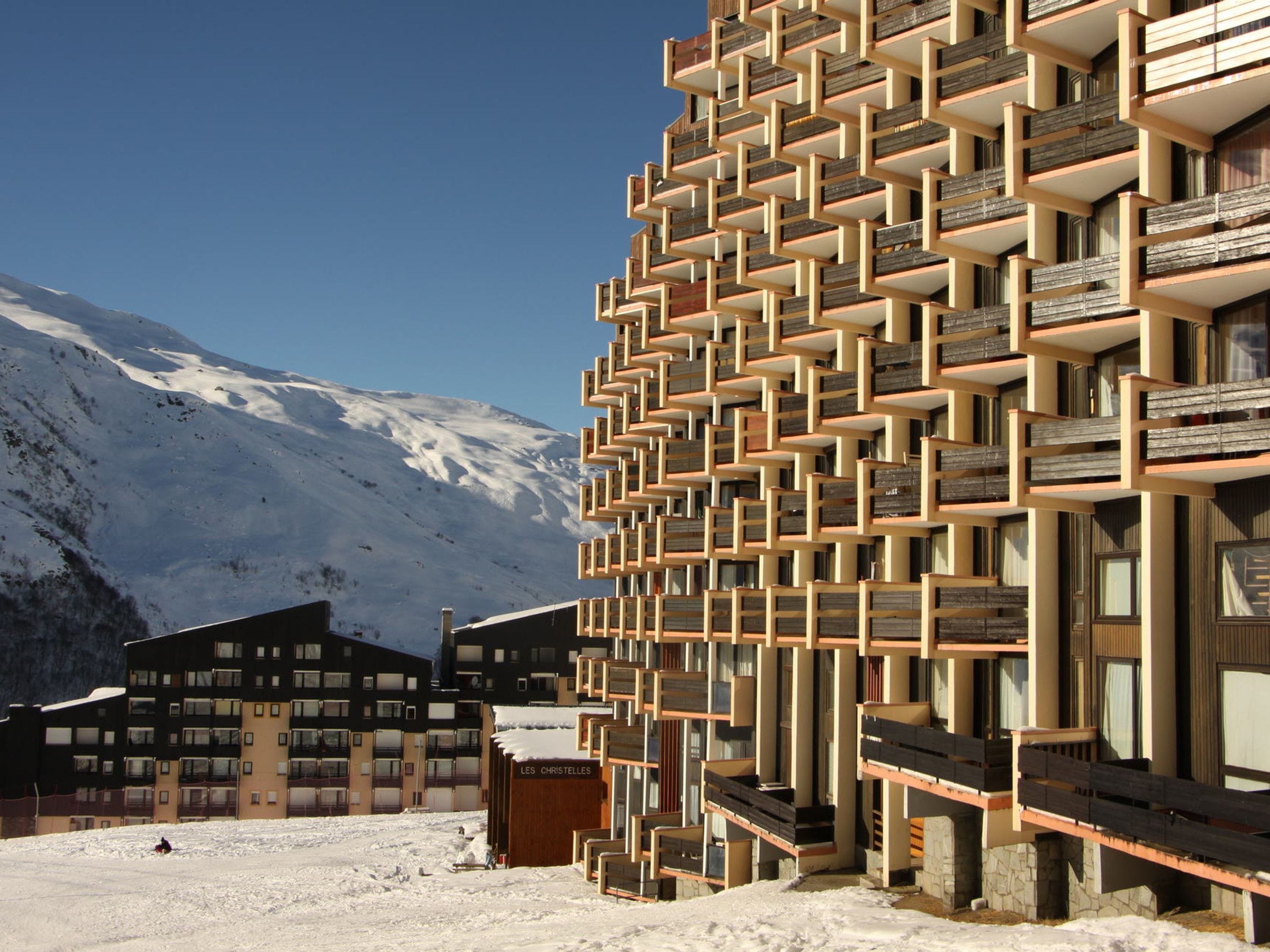 A modern building with a unique geometric facade, located in a snowy mountainous area.