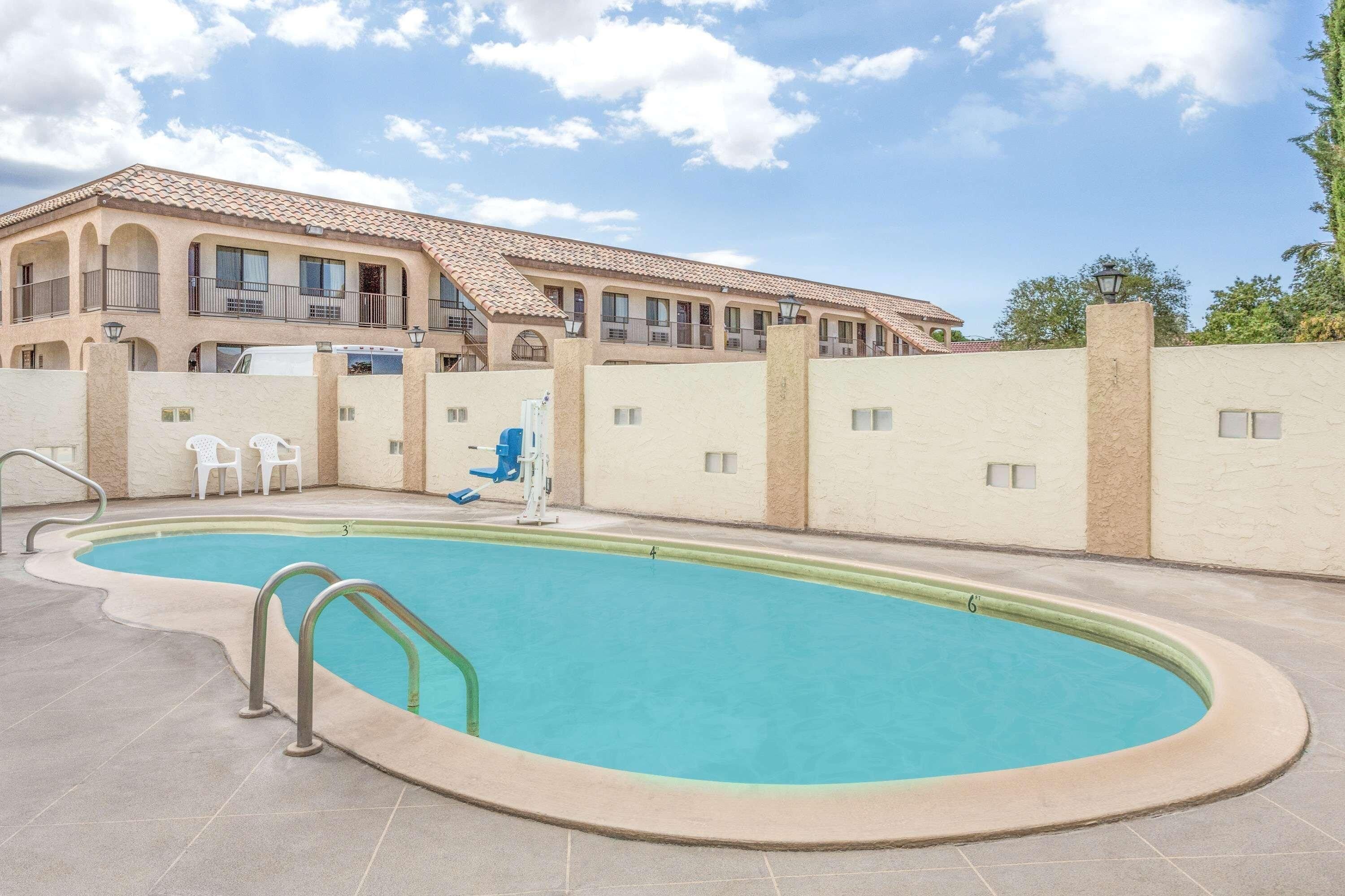 A swimming pool with a clear blue water, surrounded by a tiled deck.