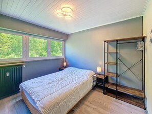 Una camera da letto con un letto, una finestra, un termosifone, una lampada e un armadio.
