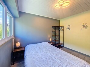 A bedroom with a bed, bedside tables, a hanging shelf, and a window. - Bright apartment, balcony - 4 guests (Les Menuires)