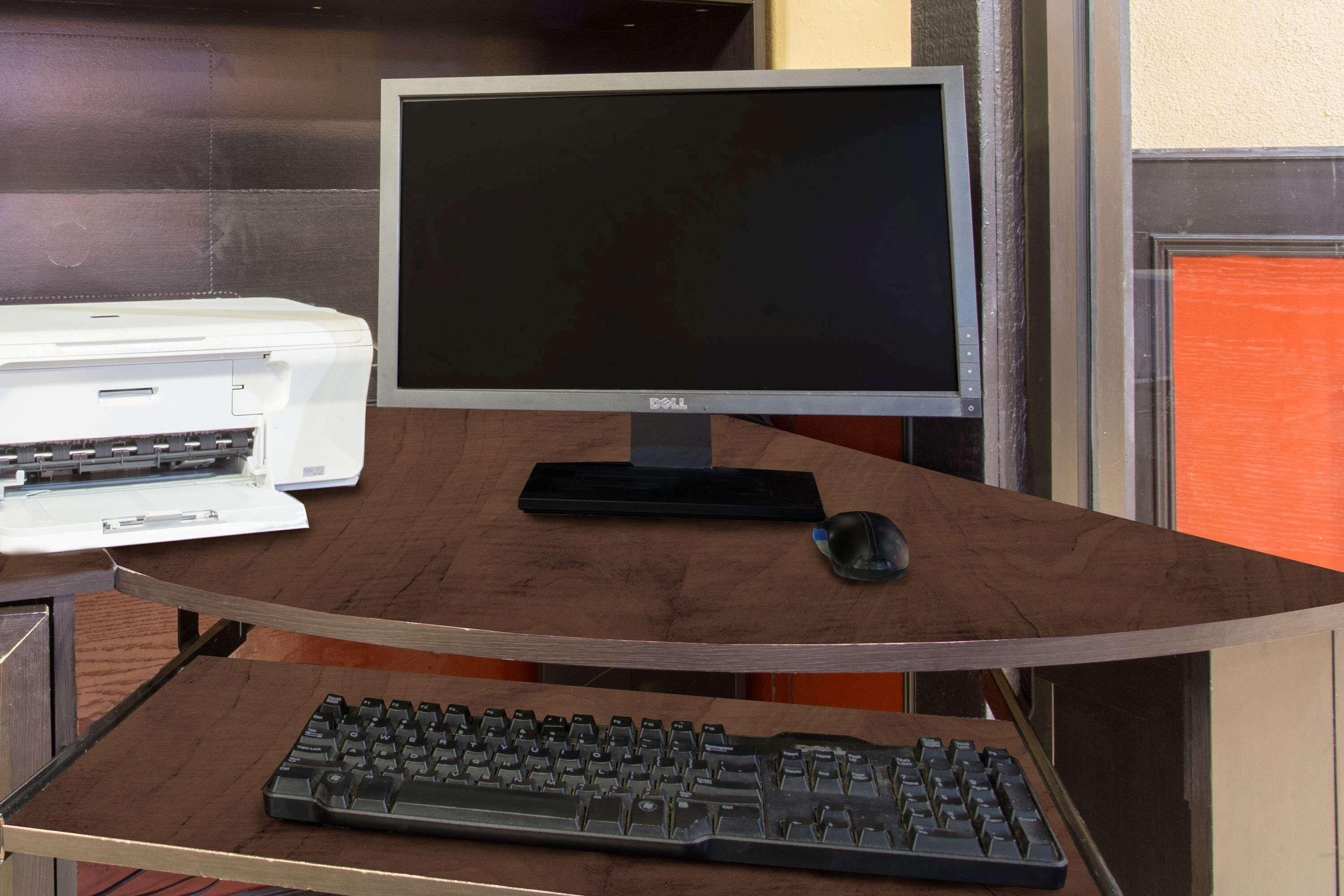A computer desk with a monitor, keyboard, and printer.