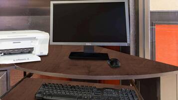 A computer desk with a monitor, keyboard, and printer.