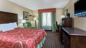 A hotel room with a bed, a desk, a chair, a television, and a window with curtains. - Texarkana Inn (Texarkana)