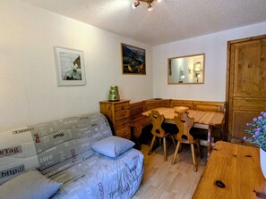 Ein gemütliches Zimmer mit einem Holztisch, einer Couch, einem Spiegel und einem Holzschrank.