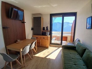 A compact living space with a dining area, kitchenette, and a sofa. - 2-room apartment - 5 guests, south balcony, L'Alpe d'Huez (Huez)