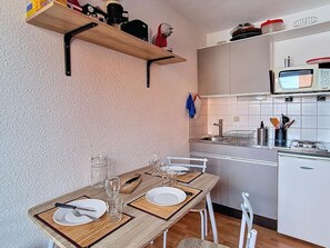 A compact kitchen with a dining area, equipped with a microwave, sink, and various utensils. - Studio at the foot of the slopes - 3 guests (Les Menuires)