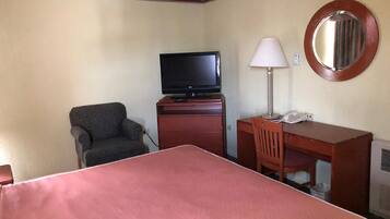 Une chambre d’hôtel équipée d’un lit, d’une télévision, d’un bureau, d’une chaise et d’une lampe.