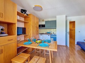 Cuina compacta amb armaris de fusta, taula de dinar per a quatre i un petit espai d'estar.