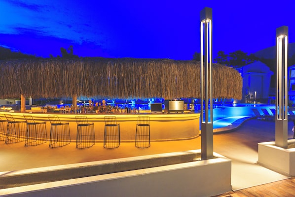 Un espacio tipo bar con piscina y sillas de descanso.