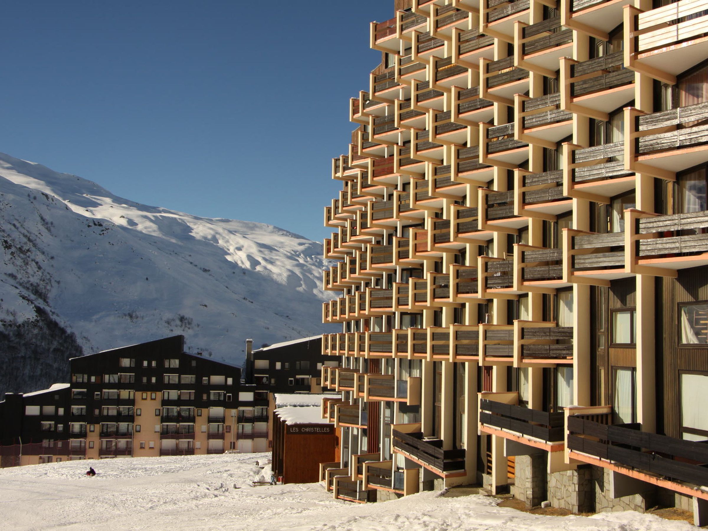 A modern building with a unique geometric facade, located in a snowy mountainous area.