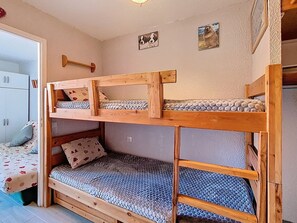 A bunk bed with a wooden frame and a lower bunk with a patterned mattress. - Studio at ski slopes - 4 guests (Les Menuires)