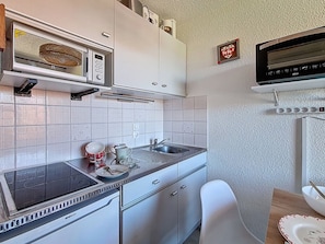 A compact kitchen with a microwave, stove, sink, and a small television. - Studio at ski slopes - 4 guests (Les Menuires)