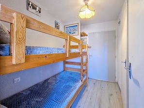 Ein Etagenbett mit blauer Matratze, einem Holzkopfteil und einer Wandleuchte.