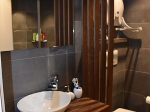 Ein Badezimmer mit einem runden Waschbecken, einem Spiegel und einer Toilette.