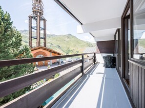 Un balcon donnant sur une montagne et un immeuble doté d’une tour.
